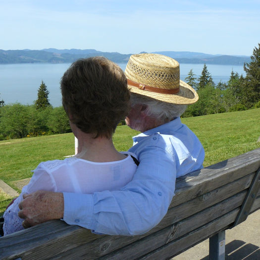 husband and wife sitting on a bench overlooking a lake